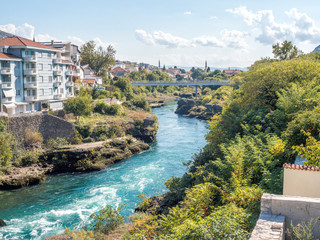 River crossing the city of Mostar with the bridge in the background