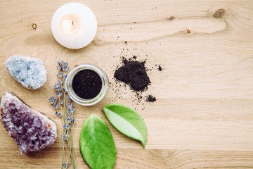 Raw activated charcoal powder in glass jar and natural green leaves next to it, natural crystal clusters for decoration. Charcoal in beauty products concept. Room for text.