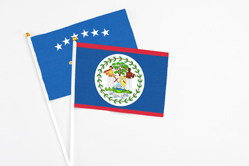 Belize and Kosovo stick flags on white background. High quality fabric, miniature national flag. Peaceful global concept.White floor for copy space.