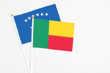 Benin and Kosovo stick flags on white background. High quality fabric, miniature national flag. Peaceful global concept.White floor for copy space.