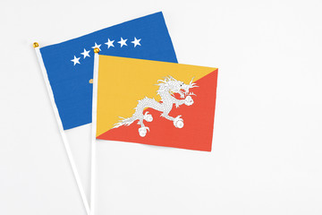 Bhutan and Kosovo stick flags on white background. High quality fabric, miniature national flag. Peaceful global concept.White floor for copy space.