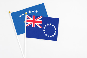 Fototapeta premium Cook Islands and Kosovo stick flags on white background. High quality fabric, miniature national flag. Peaceful global concept.White floor for copy space.
