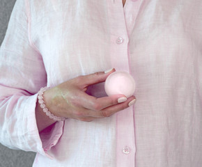Woman holding a rose quartz sphere in her hand.