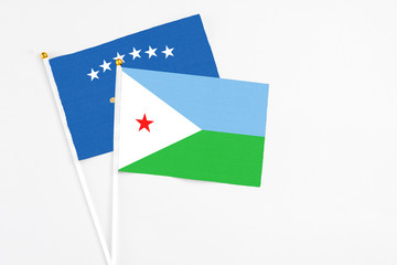 Djibouti and Kosovo stick flags on white background. High quality fabric, miniature national flag. Peaceful global concept.White floor for copy space.