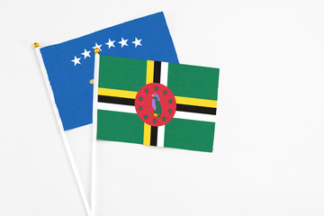 Dominica and Kosovo stick flags on white background. High quality fabric, miniature national flag. Peaceful global concept.White floor for copy space.