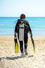 girl diver goes along the beach towards the sea