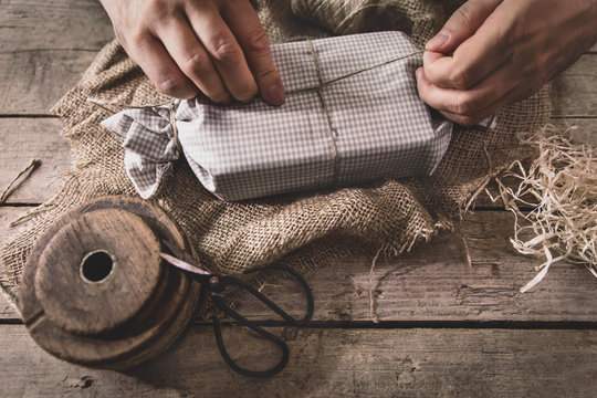 man is wrapping a gift with natural materials and organic cotton, ecological and biodegradable