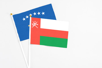 Oman and Kosovo stick flags on white background. High quality fabric, miniature national flag. Peaceful global concept.White floor for copy space.
