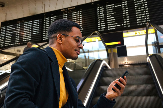 Gesch&auml;ftsman mit Brille am Flughafen Rolltreppe Airport &uuml;berpr&uuml;ft seinen Flug auf dem Handy mobil fon