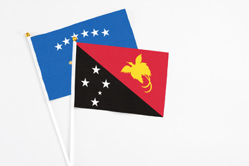 Papua New Guinea and Kosovo stick flags on white background. High quality fabric, miniature national flag. Peaceful global concept.White floor for copy space.