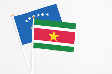 Fototapeta premium Suriname and Kosovo stick flags on white background. High quality fabric, miniature national flag. Peaceful global concept.White floor for copy space.
