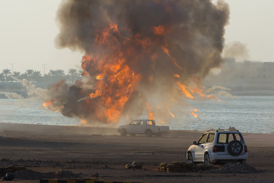 Military strike or bomb in war causes fire ball and explosion amid  cars and town in chaos. Military war concept. Strength, power, force, fire, explosion.