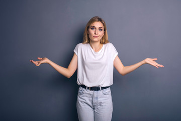 Caucasian woman in neutral casual outfit standing on a neutral grey background. Portrait with emotions: angry, pain, sickness and despair