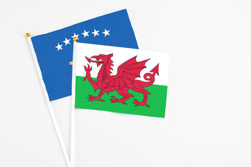 Wales and Kosovo stick flags on white background. High quality fabric, miniature national flag. Peaceful global concept.White floor for copy space.