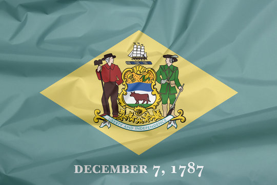 Fabric flag of Delaware. Crease of Delaware flag background, the states of America. Yellow diamond shape on green with coat of arms of the state and the date December 7, 1787.
