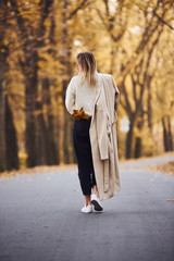 Portrait of young brunette that have a walk on road in autumn forest at daytime