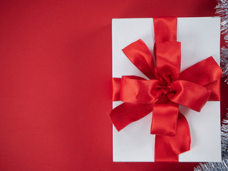 White gift box with red ribbon on red background
