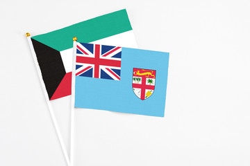 Fototapeta premium Fiji and Kuwait stick flags on white background. High quality fabric, miniature national flag. Peaceful global concept.White floor for copy space.