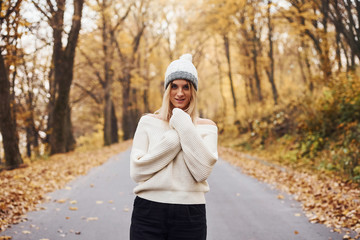 In warm clothes. Portrait of young brunette that is in autumn forest at daytime