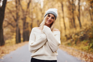 In warm clothes. Portrait of young brunette that is in autumn forest at daytime