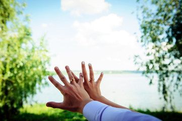 Hands of the newlyweds close-up. Gold wedding rings on the finger of bride and groom, wedding manicure. Concept of a wedding celebration.