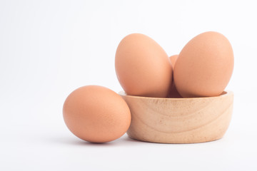Organic fresh chicken eggs in a brown wooden bowl on a white background