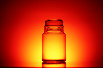 Empty glass jar on a red and black background