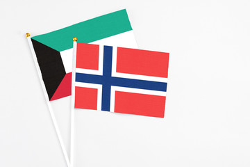 Norway and Kuwait stick flags on white background. High quality fabric, miniature national flag. Peaceful global concept.White floor for copy space.