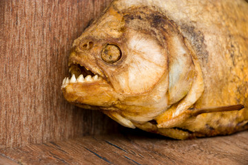 Smoked piranha on an old wooden background. Predatory river fish. River cannibal.