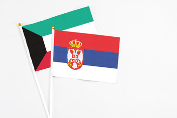 Serbia and Kuwait stick flags on white background. High quality fabric, miniature national flag. Peaceful global concept.White floor for copy space.