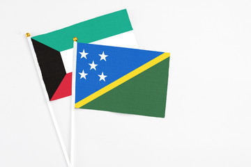 Solomon Islands and Kuwait stick flags on white background. High quality fabric, miniature national flag. Peaceful global concept.White floor for copy space.