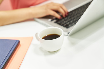 Coffee cup on the desk beside the laptop