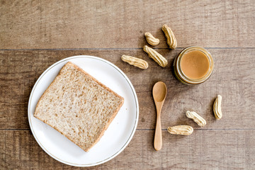 a classic slice of whole wheat bread with smooth peanut butter on wooden background