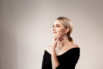 Fototapeta premium Woman with bare shoulders posing on light studio background. Professional makeup. Space for text