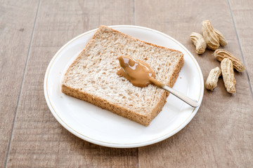 Fototapeta na wymiar a classic slice of whole wheat bread with smooth peanut butter on wooden background