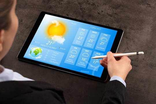 Business Woman Checking Weekly Weather Forecast On Tablet