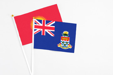 Fototapeta premium Cayman Islands and Kyrgyzstan stick flags on white background. High quality fabric, miniature national flag. Peaceful global concept.White floor for copy space.