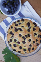 Italian sweet cake called focaccia with black grape on a wooden table
