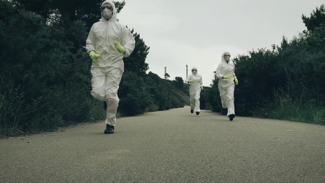 People with bacteriological protection suits running away on a lonely road