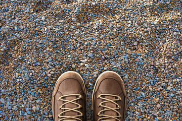 Selfie feet in brown leather shoes on stones floor, pebble beach. Foot and legs seen from above....