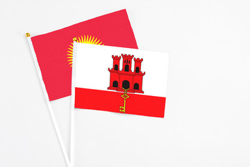 Gibraltar and Kyrgyzstan stick flags on white background. High quality fabric, miniature national flag. Peaceful global concept.White floor for copy space.
