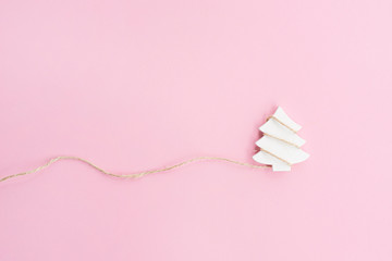 Christmas tree figurine with rope on pink background