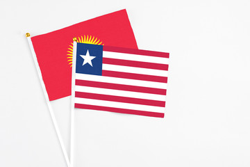 Fototapeta premium Liberia and Kyrgyzstan stick flags on white background. High quality fabric, miniature national flag. Peaceful global concept.White floor for copy space.