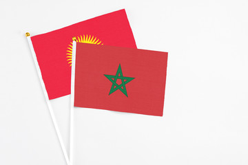 Morocco and Kyrgyzstan stick flags on white background. High quality fabric, miniature national flag. Peaceful global concept.White floor for copy space.