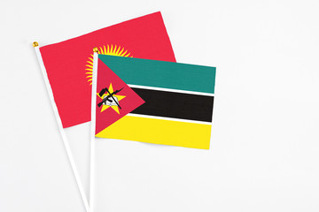 Mozambique and Kyrgyzstan stick flags on white background. High quality fabric, miniature national flag. Peaceful global concept.White floor for copy space.