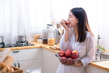 Beautiful casual Asian woman is about to bite an apple, young woman eating fresh red apple