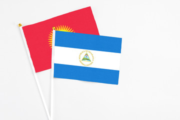 Nicaragua and Kyrgyzstan stick flags on white background. High quality fabric, miniature national flag. Peaceful global concept.White floor for copy space.