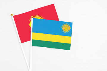 Rwanda and Kyrgyzstan stick flags on white background. High quality fabric, miniature national flag. Peaceful global concept.White floor for copy space.