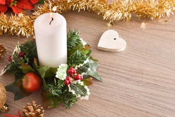 Candle on table with Christmas floral arrangement and heart top