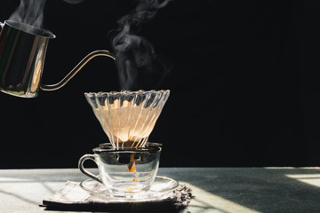 The steam from a cup or a pot of coffee on the old wood table and black background, Warm drinks make good healthy, Drip coffee brew, easy to make at home, Selective focus.